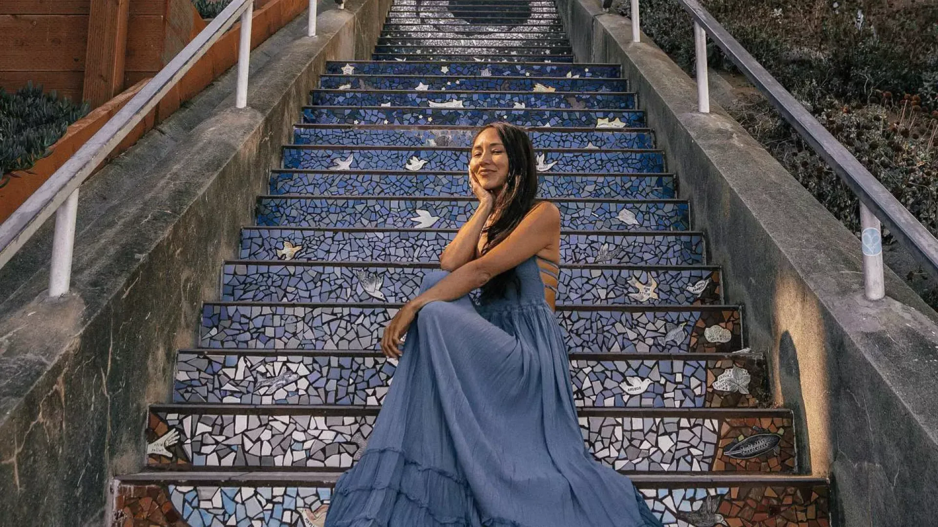 Une femme pose assise sur les escaliers carrelés de la 16e Avenue dans le quartier Sunset de San Francisco.